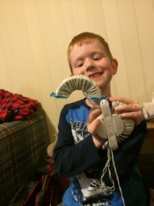 Charlie making a pompom on a Clover pompom maker