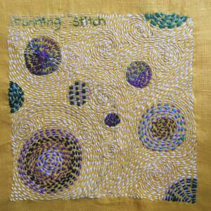 Embroidered running stitch sampler with swirls and circles.