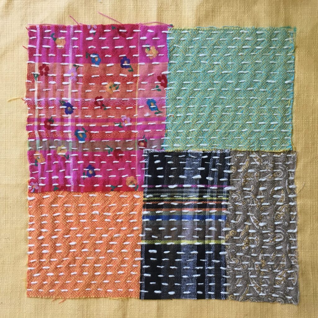 Blocks of cotton fabric stitched to a background using running stitch.