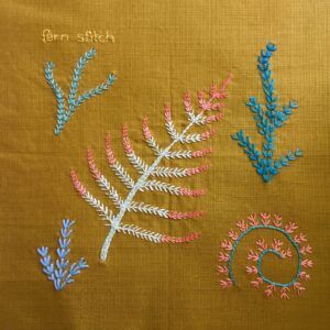 Fern stitch leaves and spirals embroidered on a vintage linen serviette.