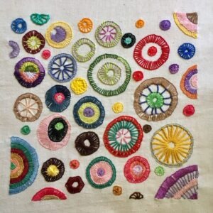 Embroidered sampler with many circles stitched with buttonhole or blanket stitch.