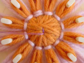 Stitching a button to the center of a loomed flower