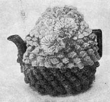 crochet tea cozy with bobbled texture and pom-poms