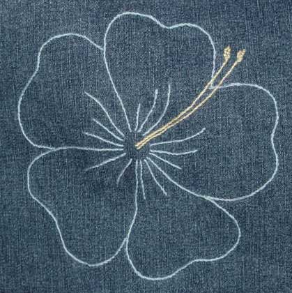 Denim cushion with an embroidered hibiscus