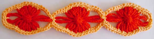 Three lozenge shaped flowers with crocheted edging