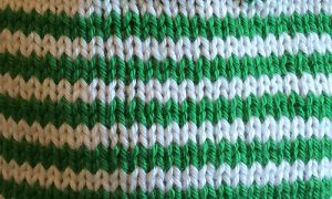 Stocking stitch knitting in rows of green and white stripes