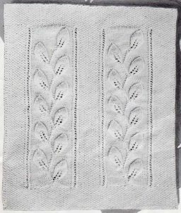 Knitted worsted weight baby blanket with two vertical panels of travelling leaves.