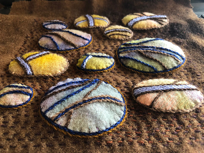 Dimensional wool blanket pebbles on a felt/wool blanket background.