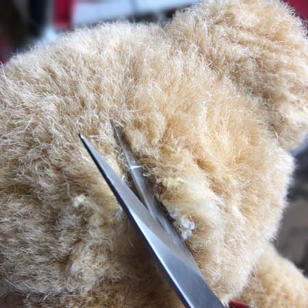 Cutting open the seam on a teddy bear