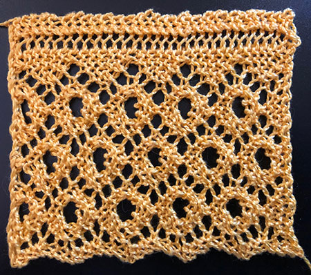 A knitted lace edging featuring lace diamonds with a large eyelet in the centre of each