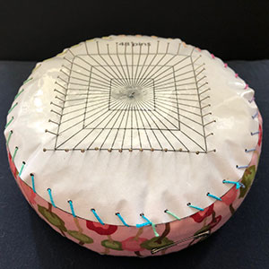 A teneriffe lace cushion with a paper plan sewn to the top