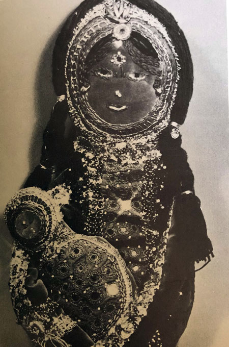 Black and white photo of a Madonna and Child, richly decorated with embroidery and small, round mirrors.