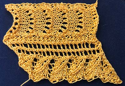 Knitted sample of a feather and fan lace with a leaf shaped edging.