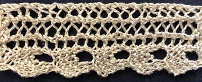 Knitted sample of a thin lace with a ric-rac shaped edging.