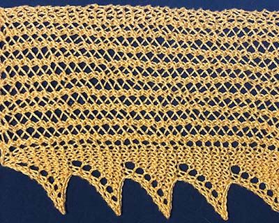 Knitted sample of a very wide lace with a wide band of lace stripes and triangular edging.