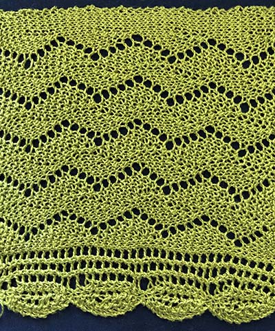 Knitted sample of a wide zig-zag lace border with knit in oval edging.