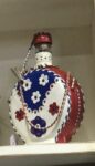 A red, white a blue leather covered water bottle with floral design