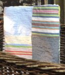 A simple quilt made of four large squares of different striped fabrics.