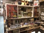 A painted cabinet full of brightly coloured glassware and pottery