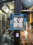 A small square wall clock with blue tiled frame