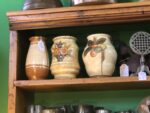 Three small stoneware vases. Two have flowers painted on them.