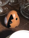 A caramel coloured ceramic egg with vertical sawtooth stripes and spots in black